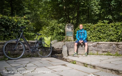 Udo sitzt an der Ruhrquelle bei Winterberg.