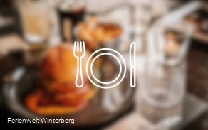 Ein verschwommenes Bild eines gedeckten Tisches mit Speisen und Getränken mit der Zeichnung eines Tellers und Besteck im Vordergrund. Dieses Bild dient als Symbolbild für Restaurants.