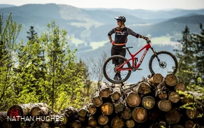 Bikerin mit Mountainbike auf Holzstapel